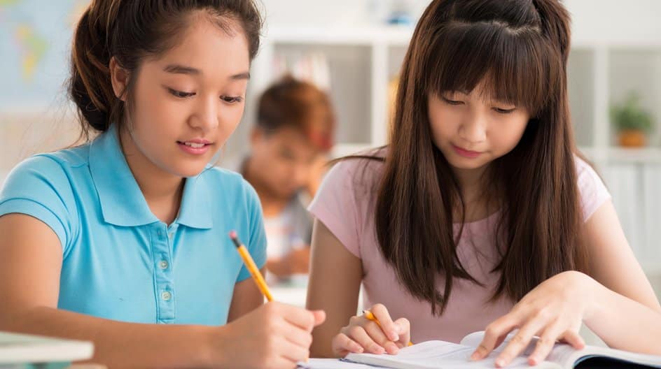Two students writing at a desk